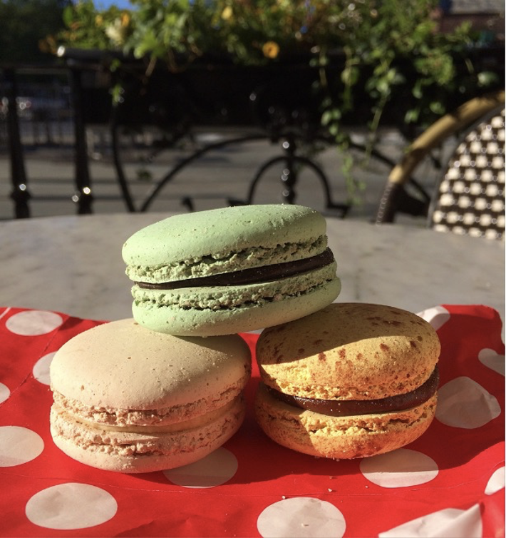 A stack of three macaroons on a red polka dotted table